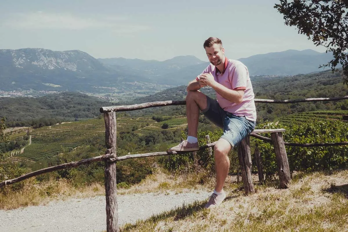 Primoz Lazar sitting on a wooden fence above a valley